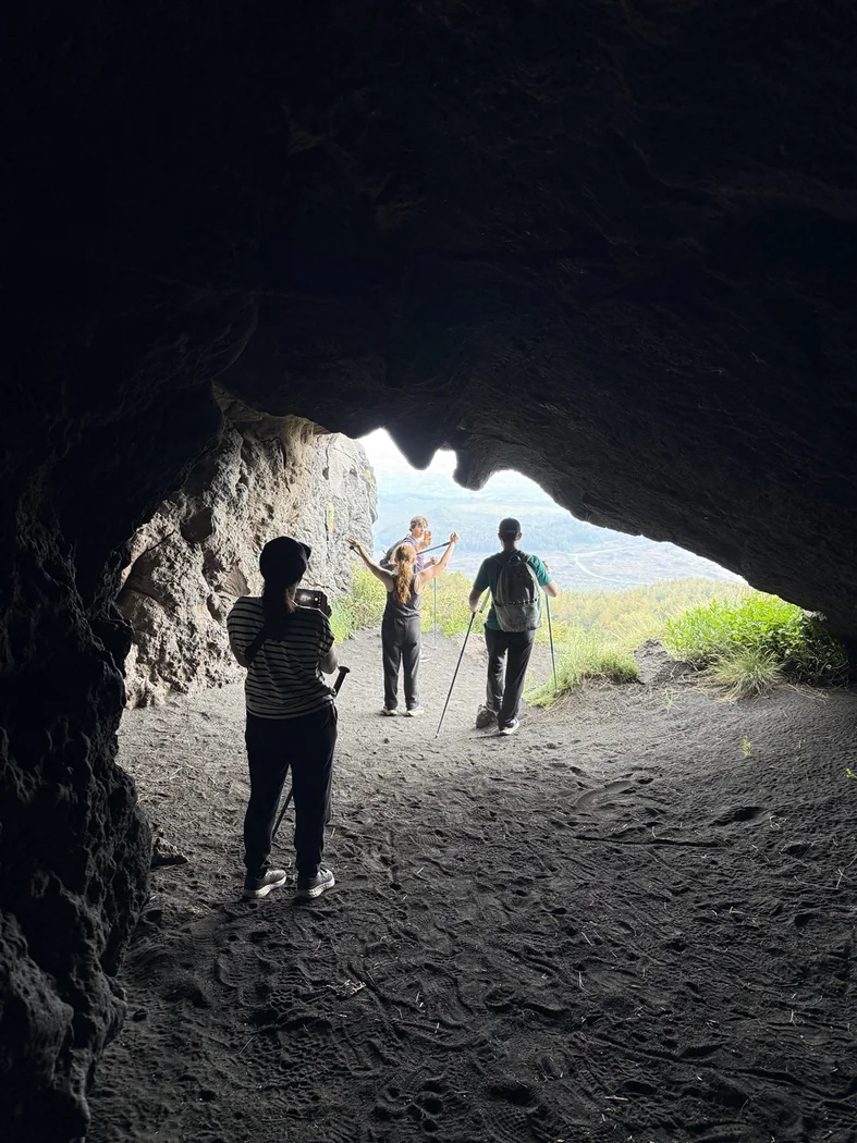 Hikers leaving a lava cave on Mount Etna and returning to daylight