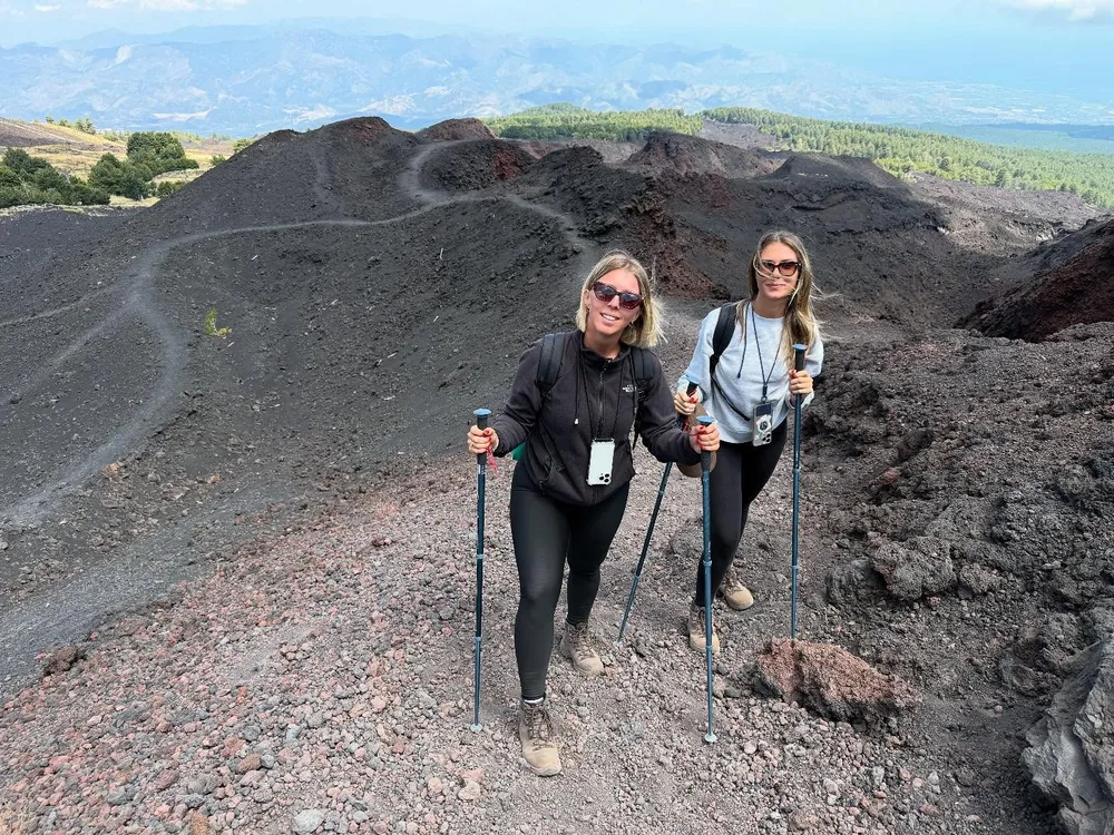 Hikers walking across the volcanic landscape of Mount Etna