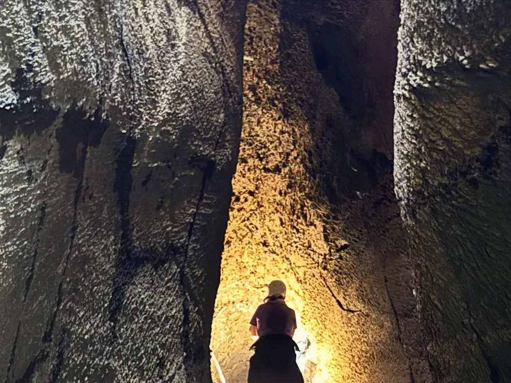 A visitor exploring a lava cave on Mount Etna